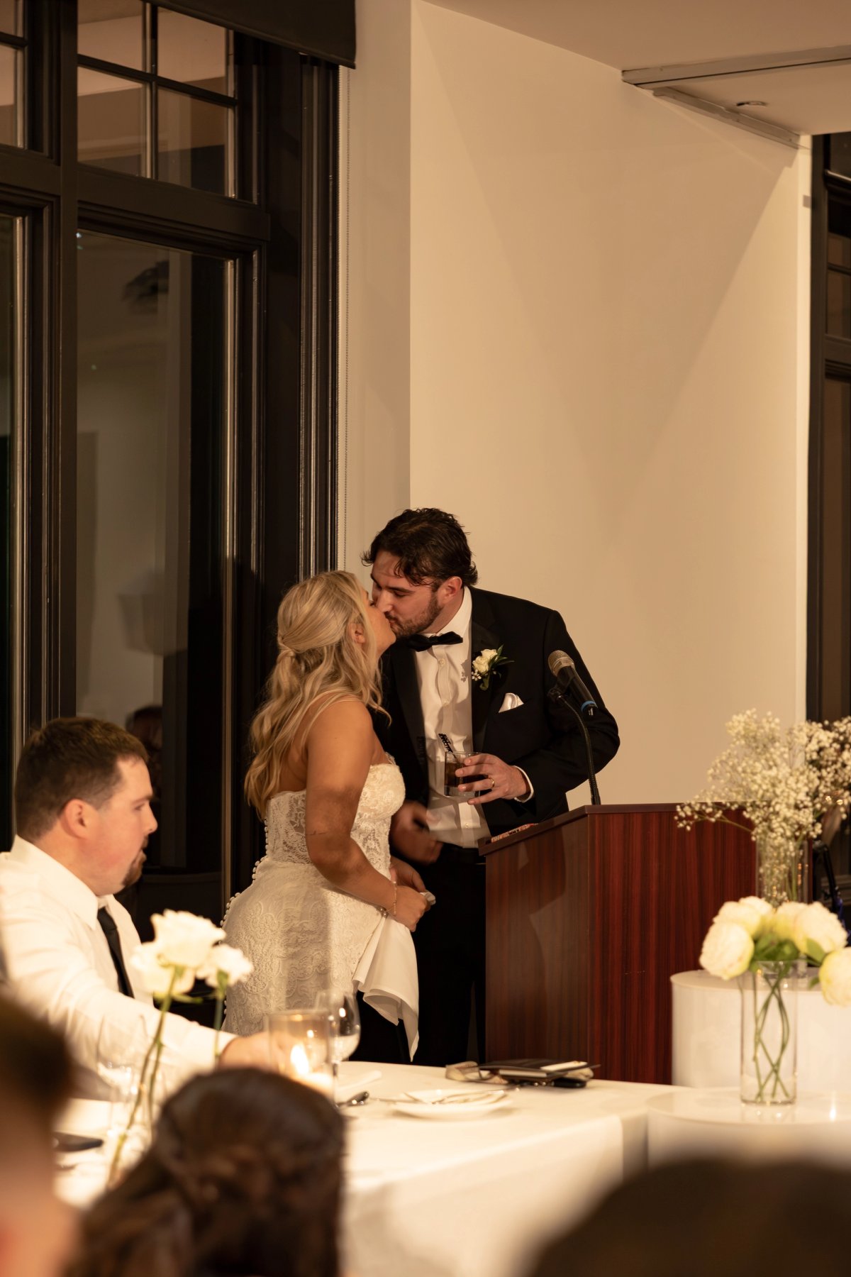 Candid moment during speeches at a Barrie wedding where the bride and groom kiss