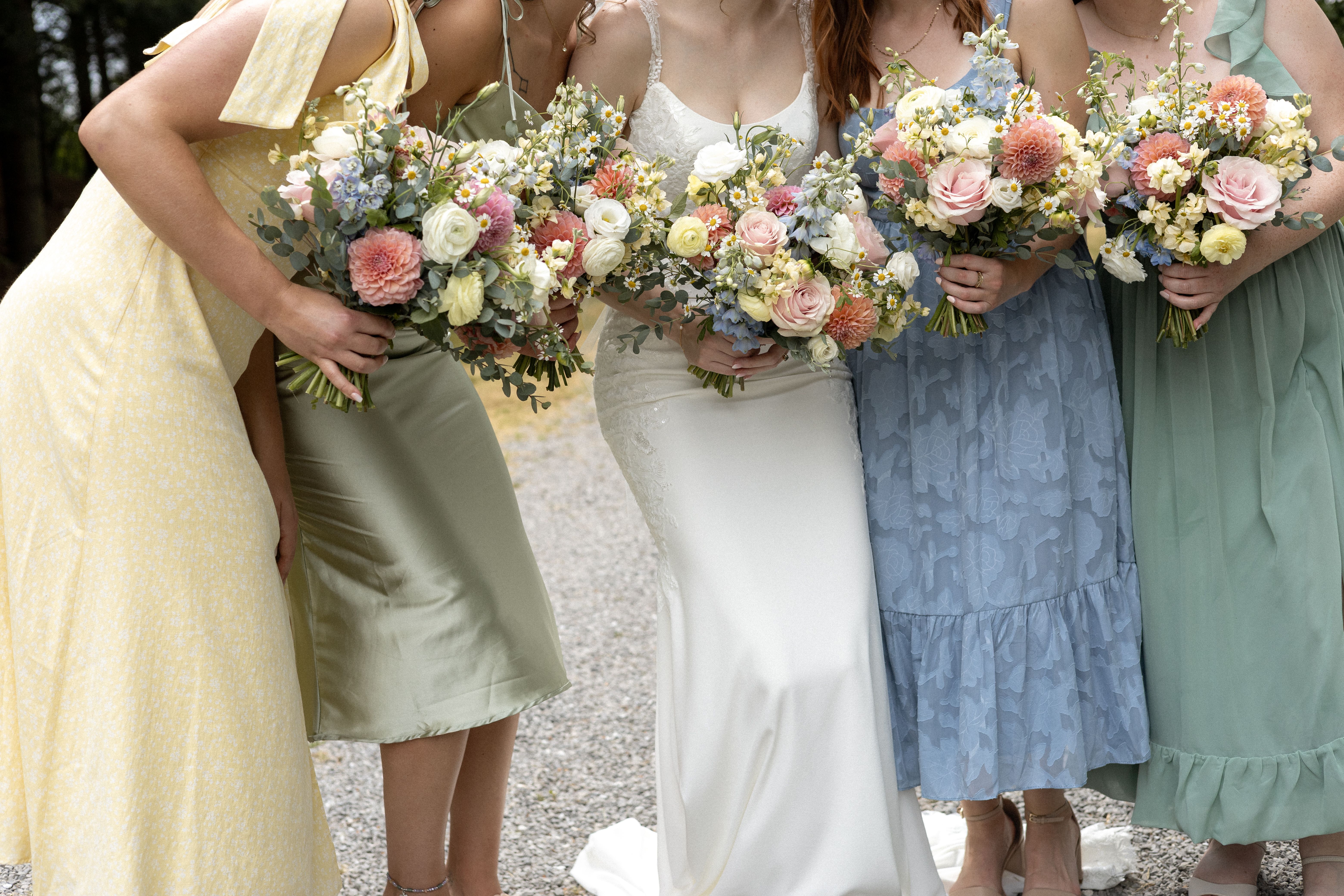 close up of colourful bridesmaid dresses and bouquets during summer wedding in niagara, ontario