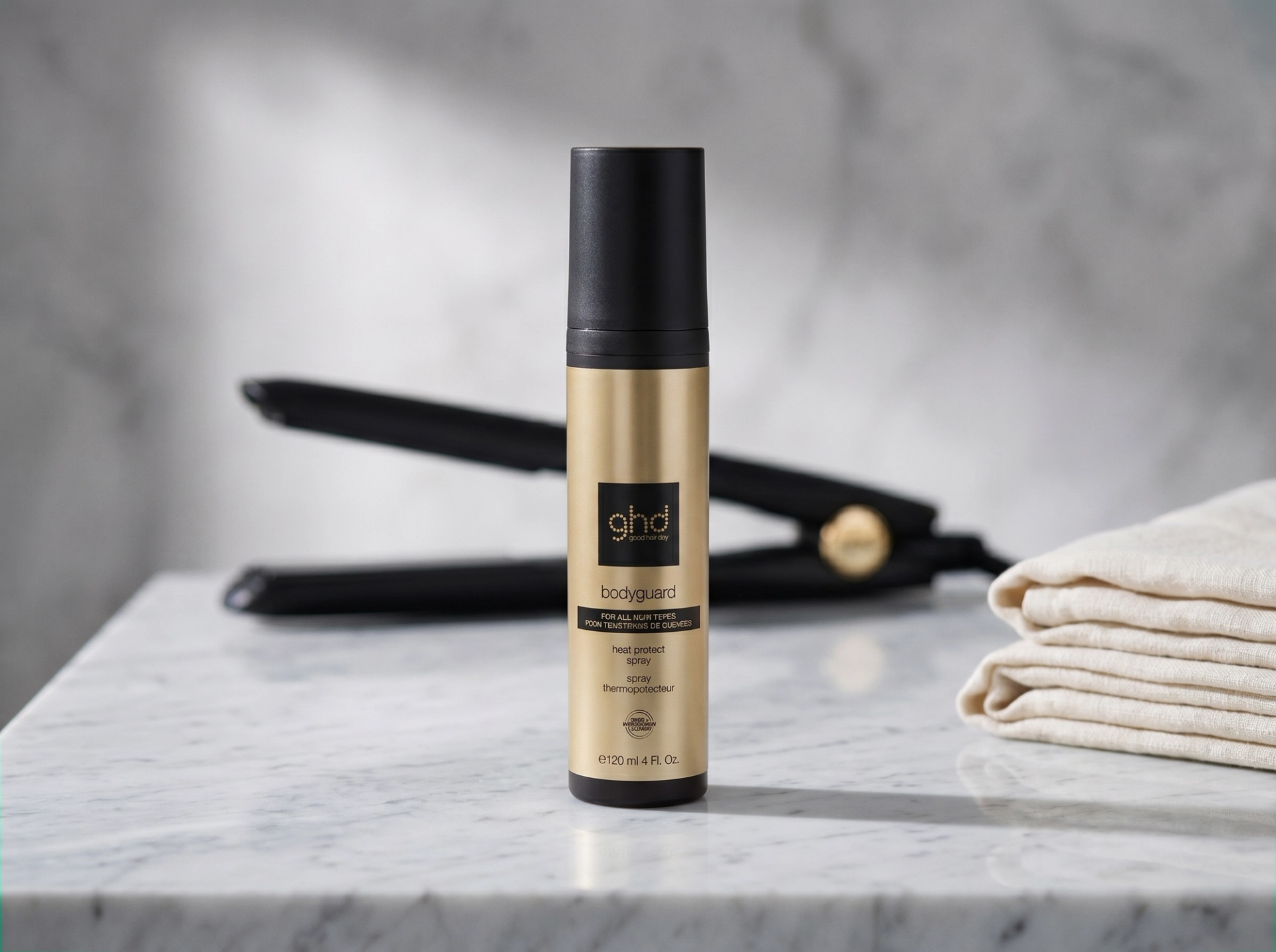 Editorial Bathroom-Vanity-Scene: ghd Bodyguard auf Carrara-Marmor stehend, schwarzes ghd Platinum+ Glätteisen im weichen Bokeh dahinter, gefaltete Cream-Linen-Tücher rechts – Premium Salon-Mockup