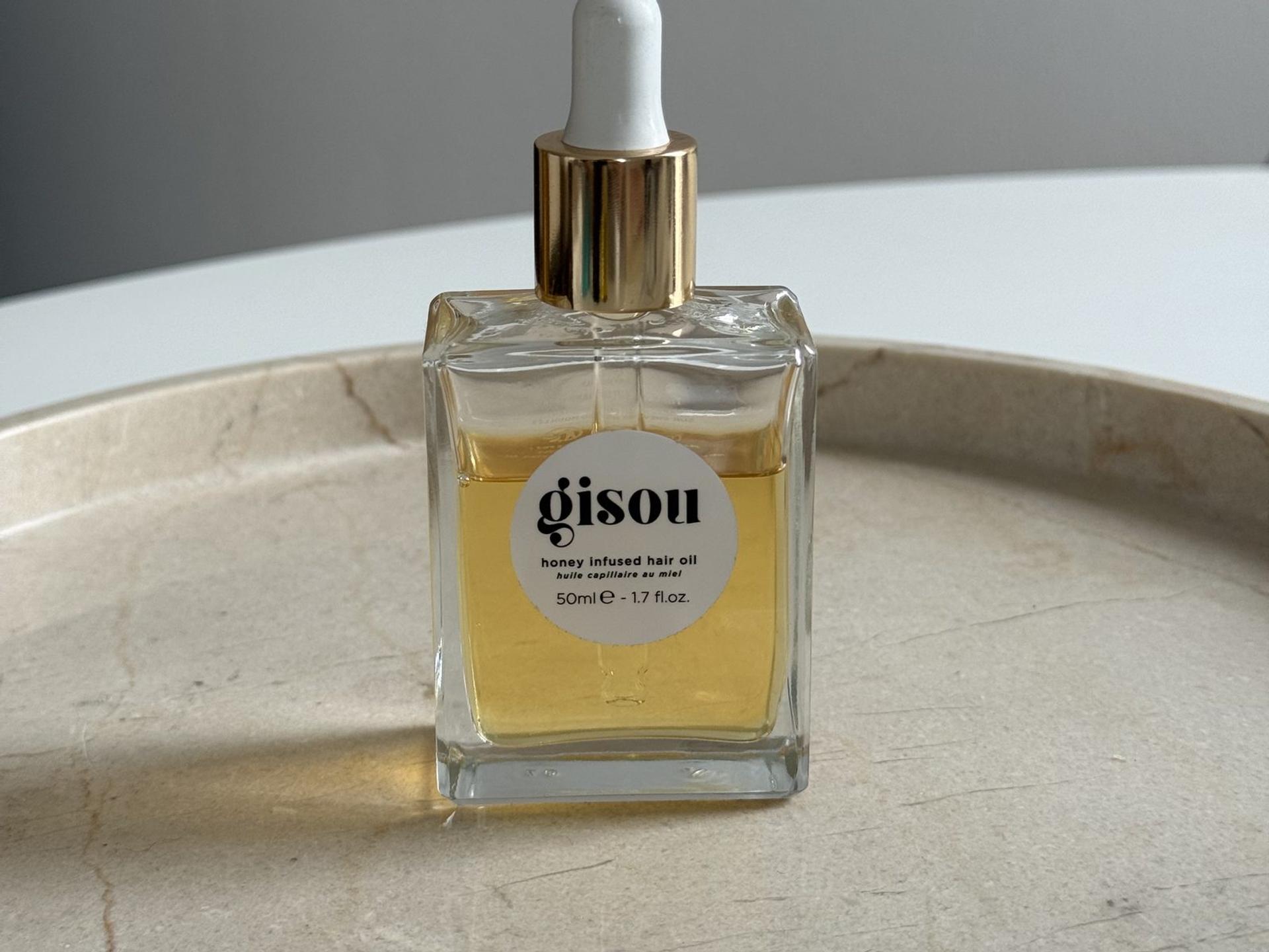 Gisou Honey Infused Hair Oil steht auf einer Marmorablage, unser Praxistest-Flakon