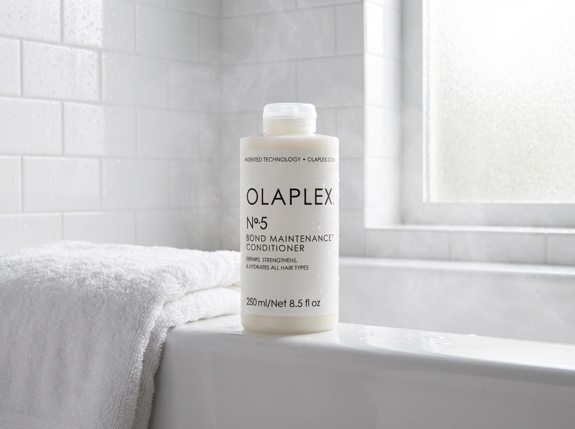 Olaplex Nº.5 Conditioner auf weissem Badewannenrand mit gefalteten Handtüchern