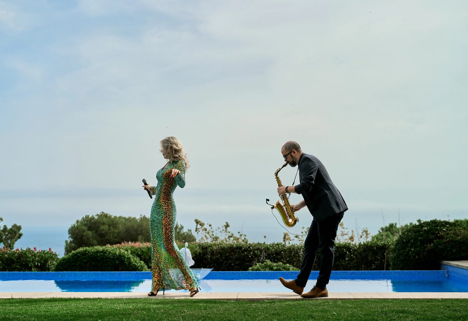 A singer and a saxophonist beside a pool