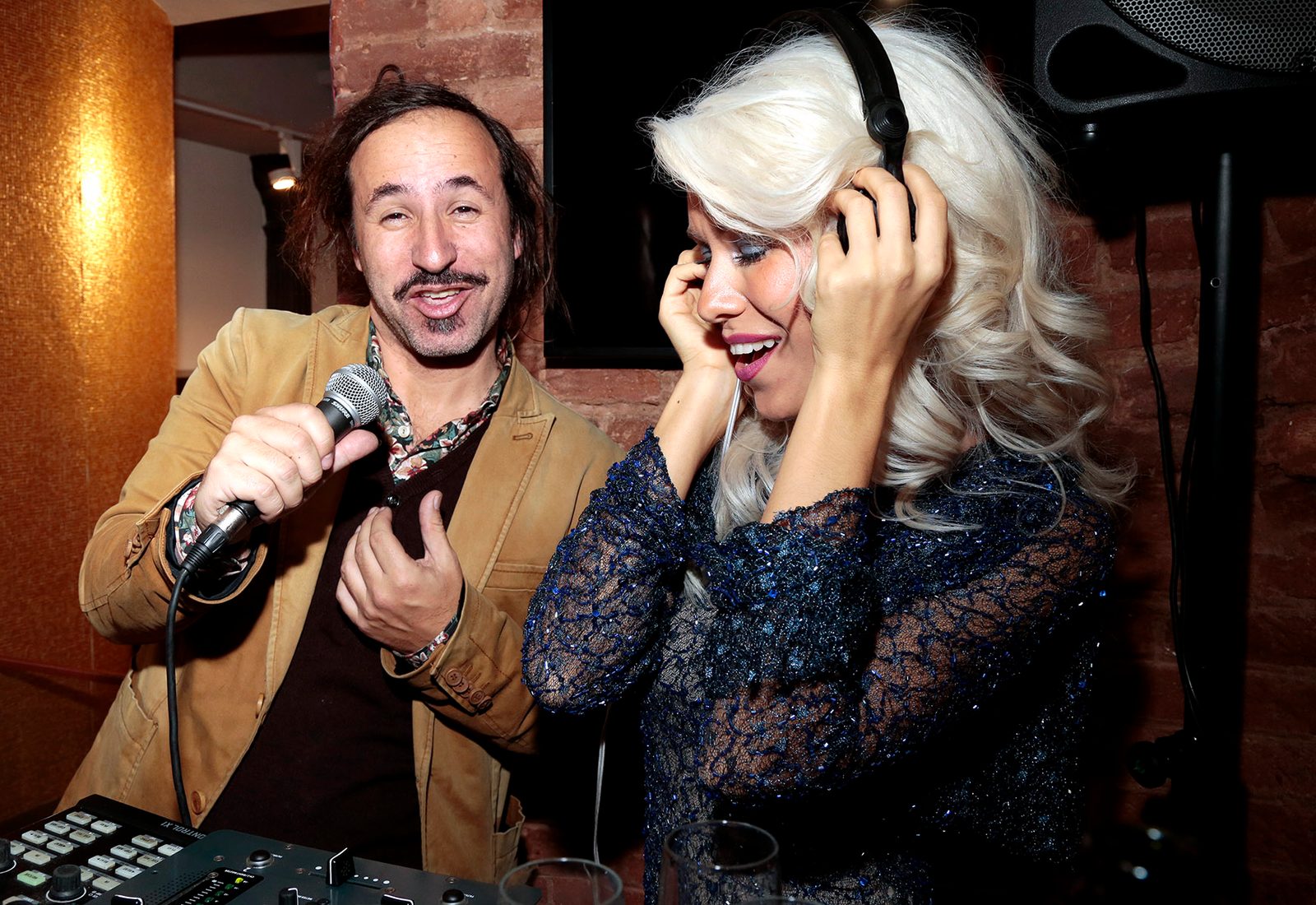 Woman wearing headphones beside a man with a microphone and a mixing desk