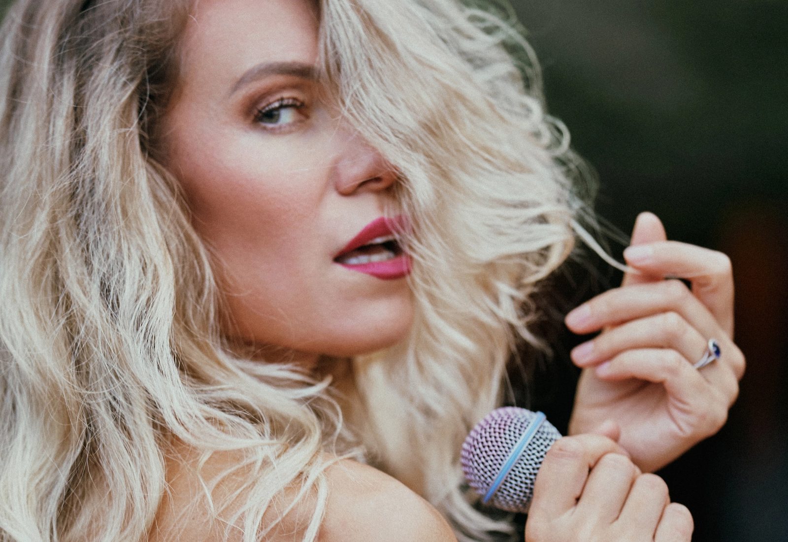 Portrait of Marina Caró with a microphone outdoors