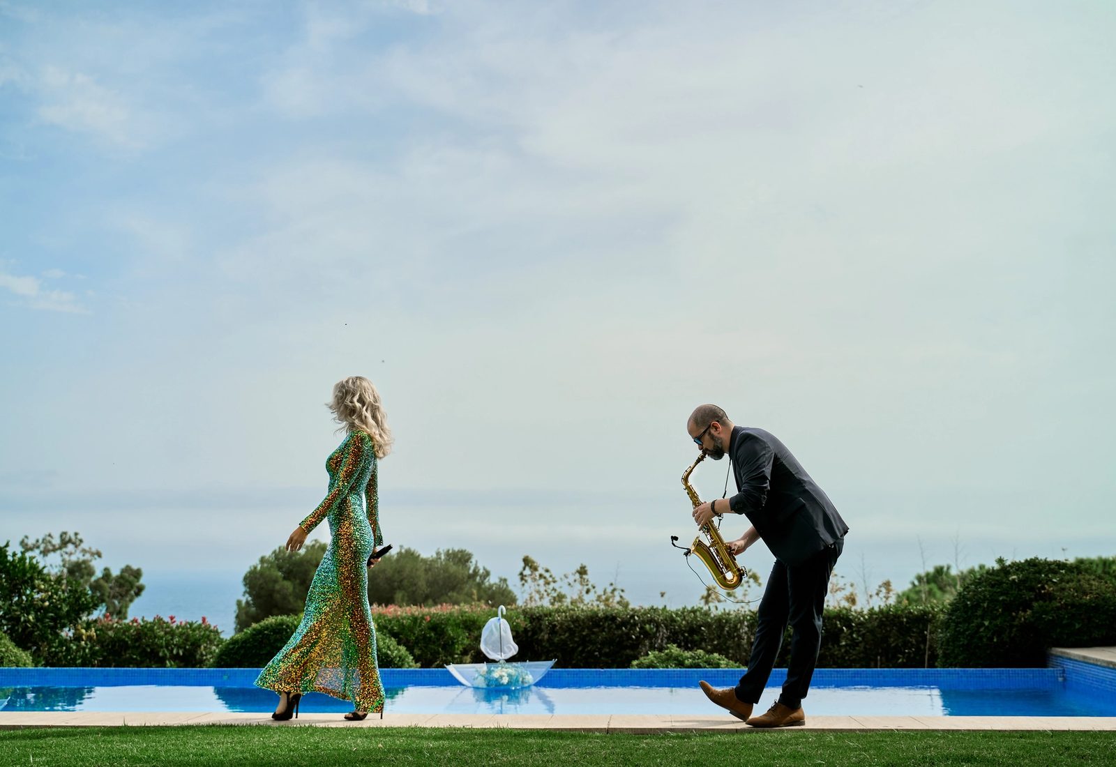 A singer and a saxophonist beside a pool