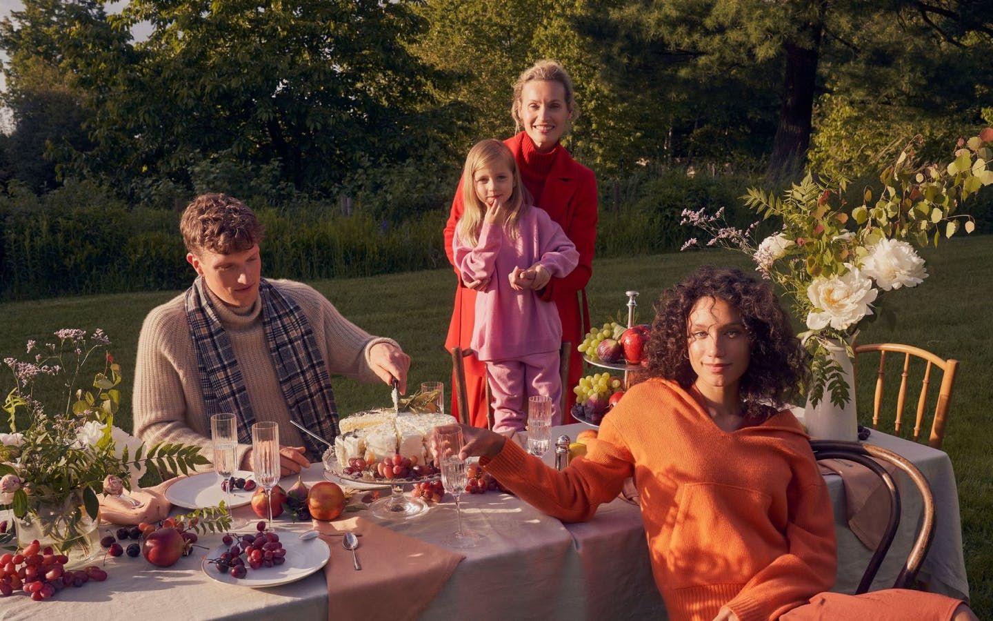 A family sits at a table outdoors eating while wearing Gobi cashmere