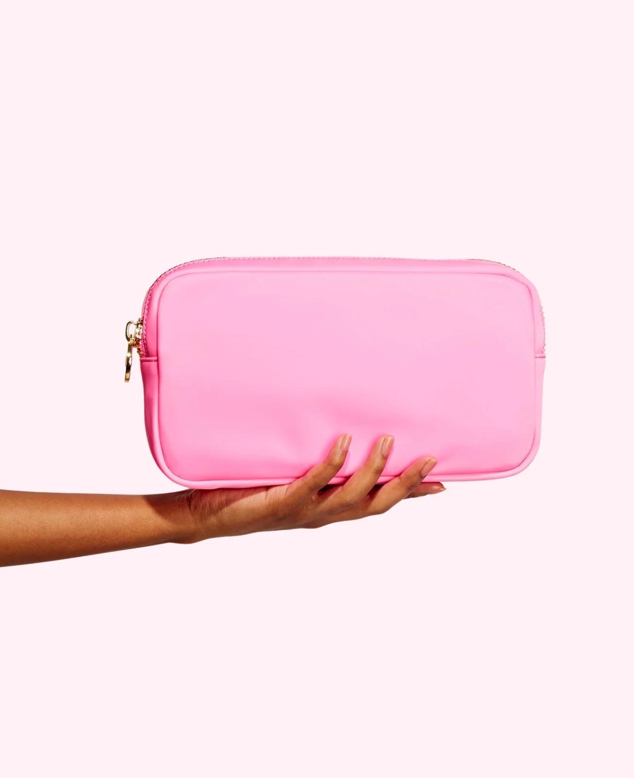 A hand holding a pink Stoney Clover Lane pouch