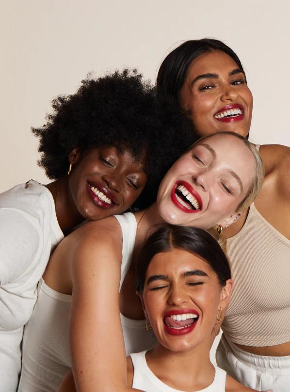 Four smiling women wearing Lip Lab lipstick