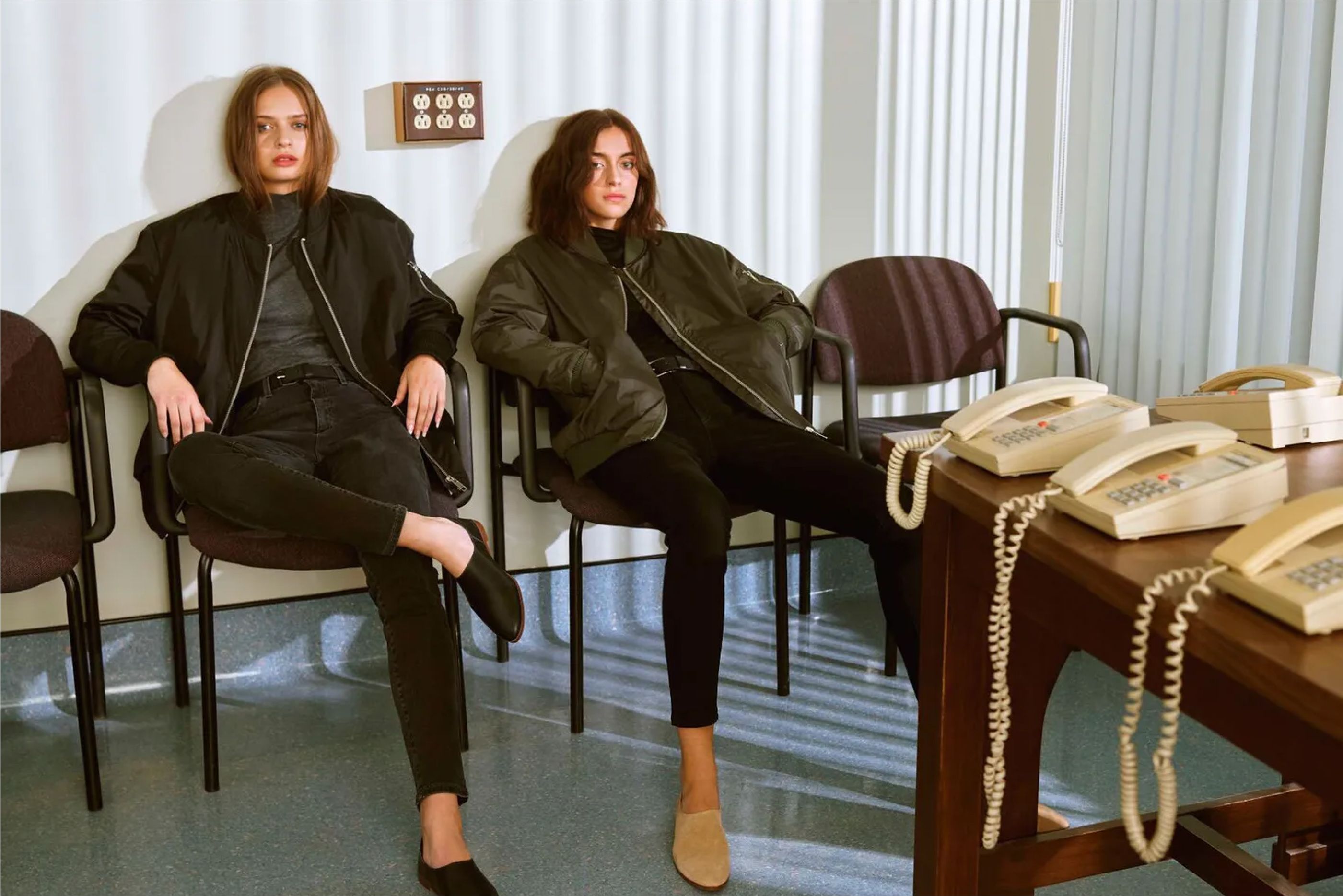 Two women sitting an a reception area wearing Frank and Oak