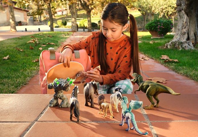 Young girl plays with Schleich dinosaur and animal toys