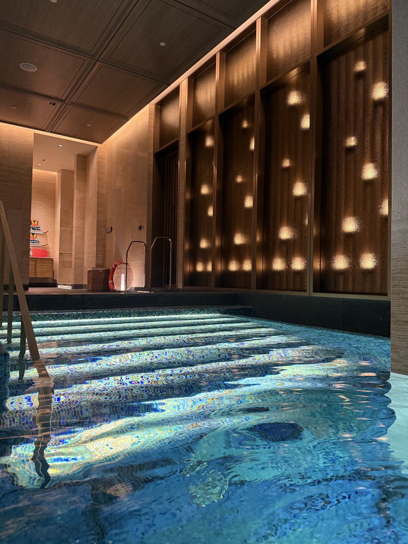 A blue-mosaic vitality pool with glowing lattice walls at the Cirua Bathhouse