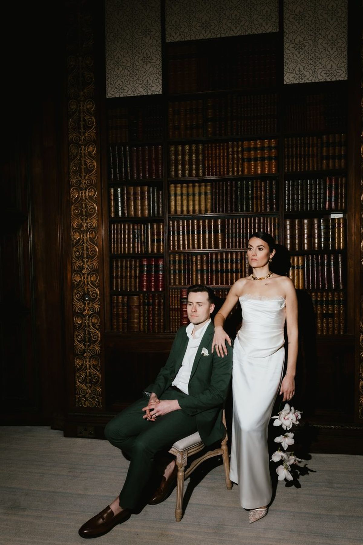 Couple portrait in library with dark bookshelves