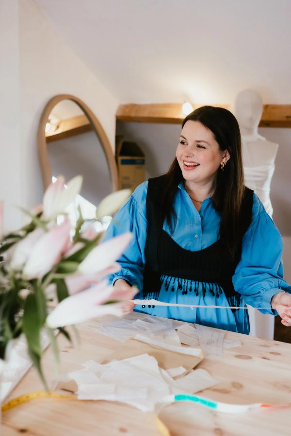 Laura, bridal designer, working intently on a wedding dress in her Bristol studio, showcasing expert craftsmanship