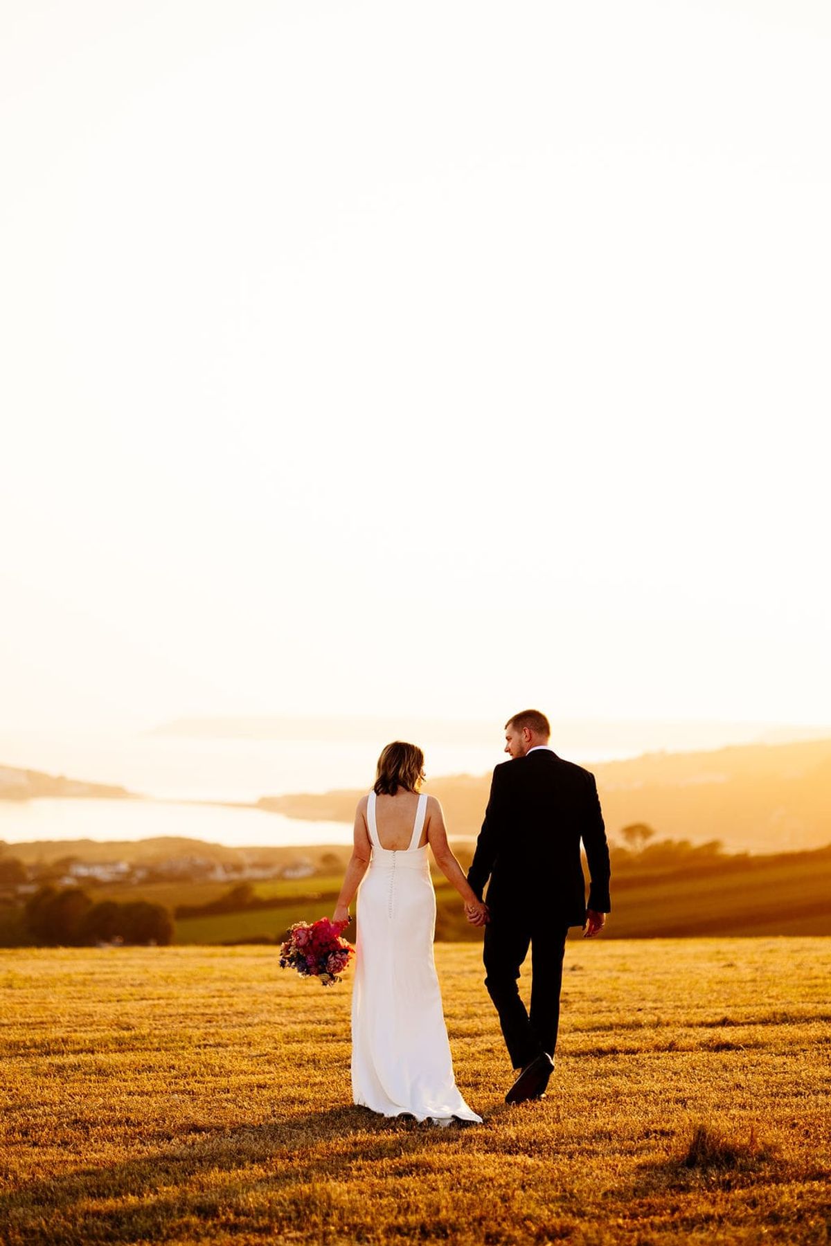 Romantic couple walking together at sunset in golden field landscape