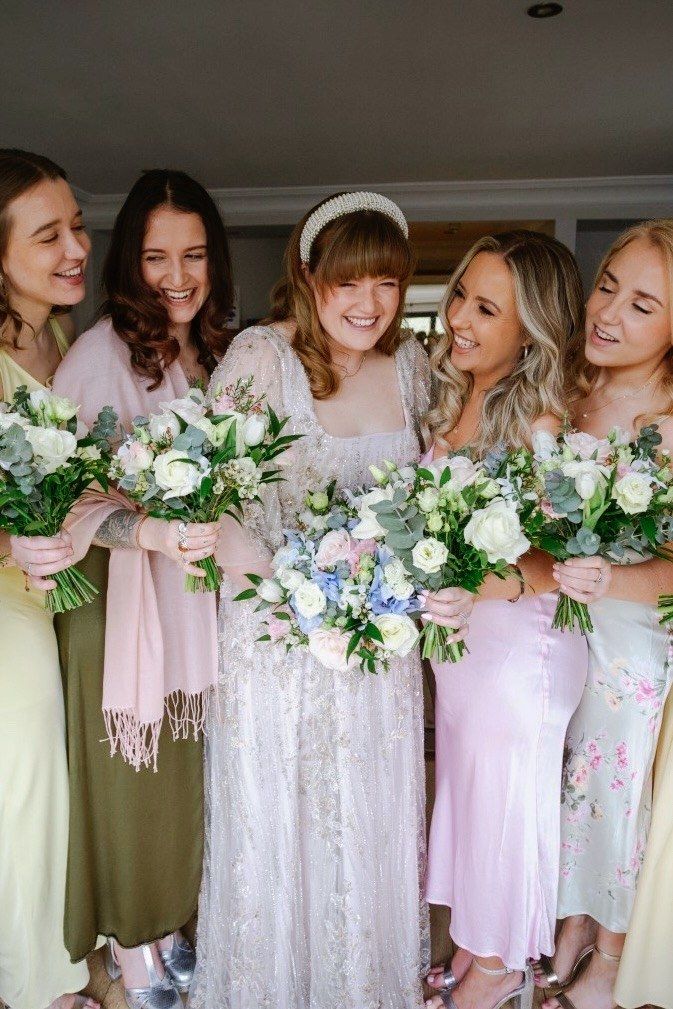 Bride laughing with bridesmaids, all holding bouquets