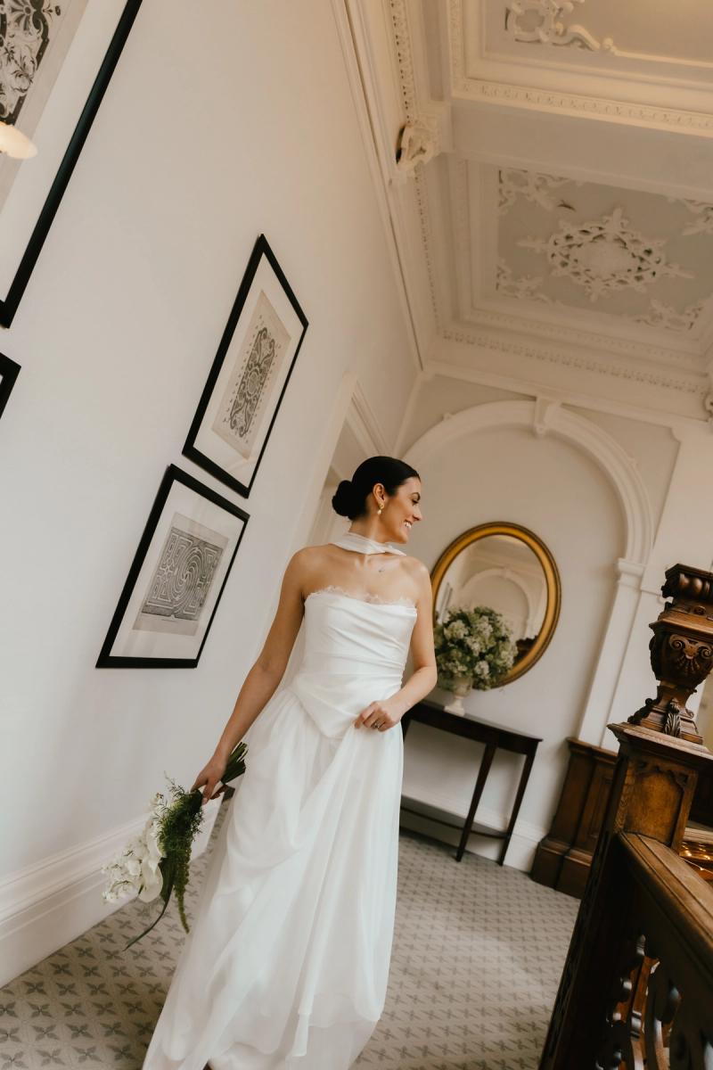Bride on staircase wearing a flowing corset and skirt combination with sheer neck scarf