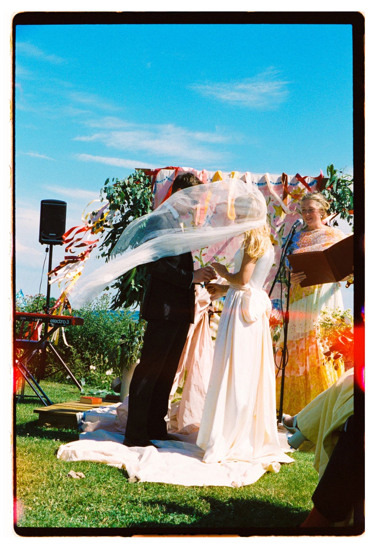 Film photograph of an outdoor ceremony with a restored vintage veil lifting in the wind