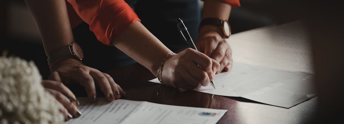 person in orange long sleeve shirt writing on white paper