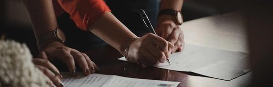 person in orange long sleeve shirt writing on white paper