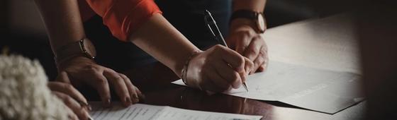 person in orange long sleeve shirt writing on white paper