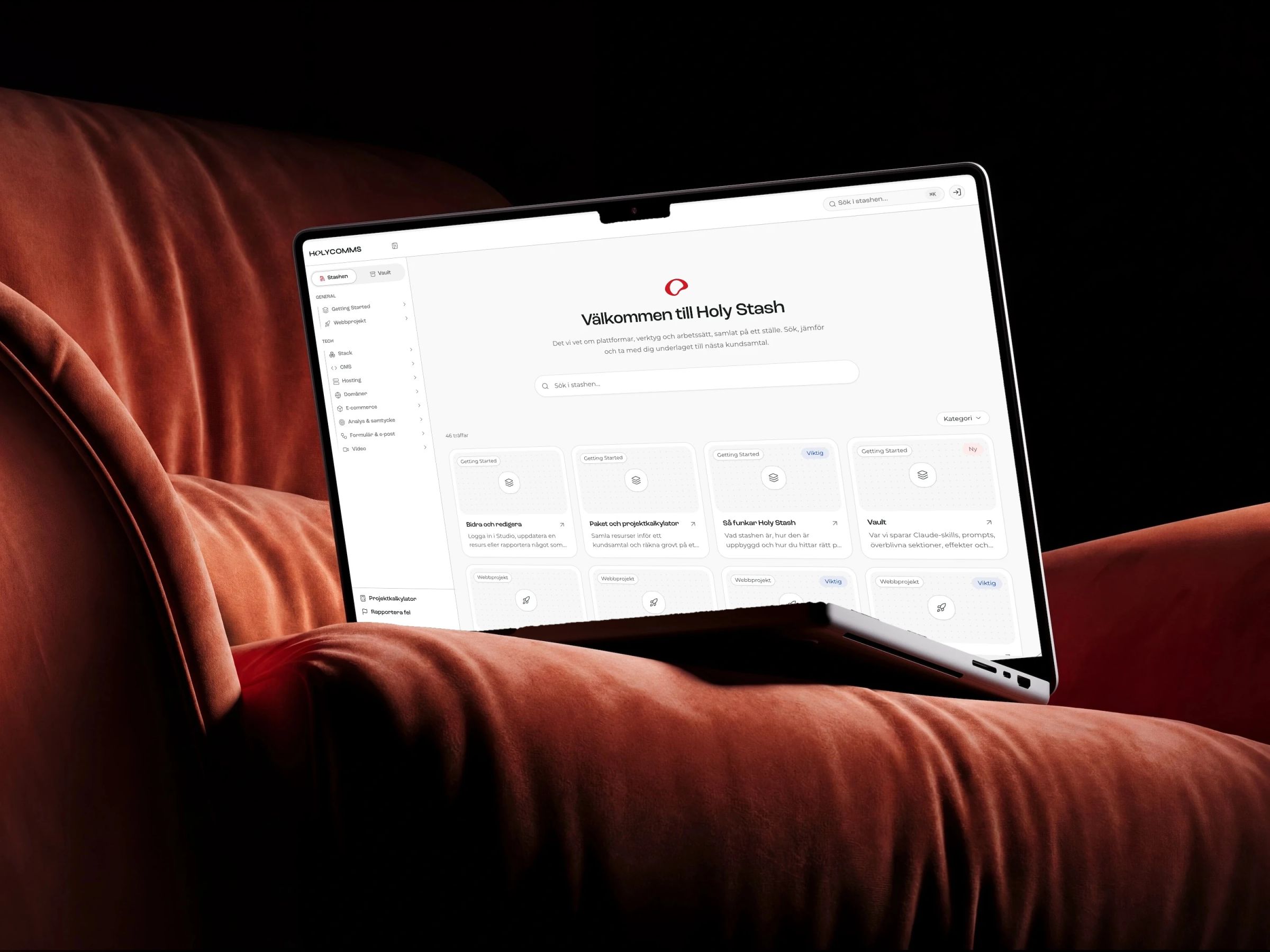 Holy Stash's start page on a MacBook resting on a red velvet sofa
