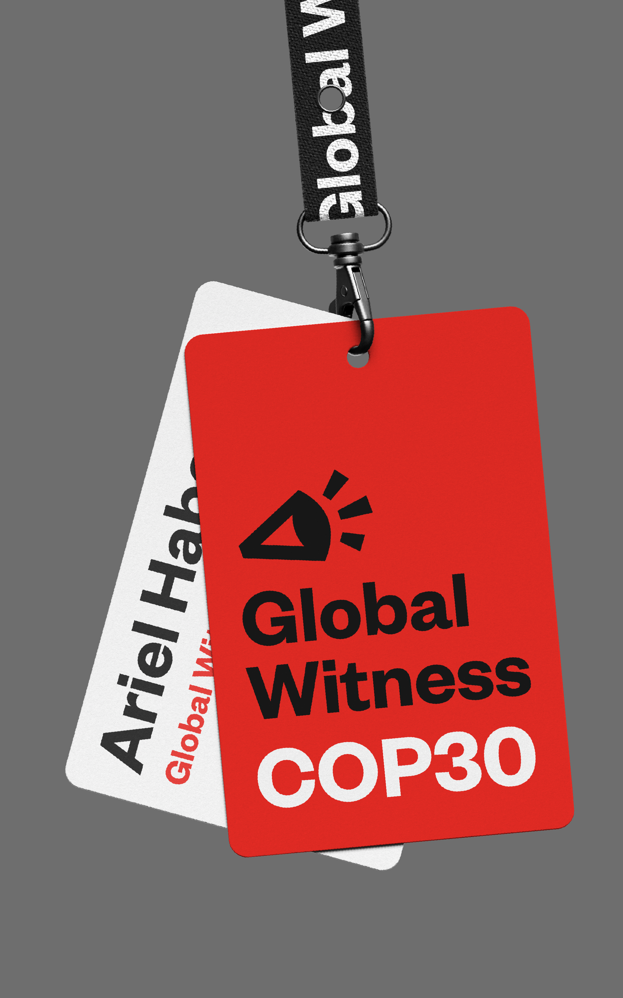 A lanyard for COP30 is shown against a grey background. There are two cards connected by a clip, the one is red and has the Global Witness logo, with COP30 underneath; the other has the personal ID card with a persons name on it, and their position