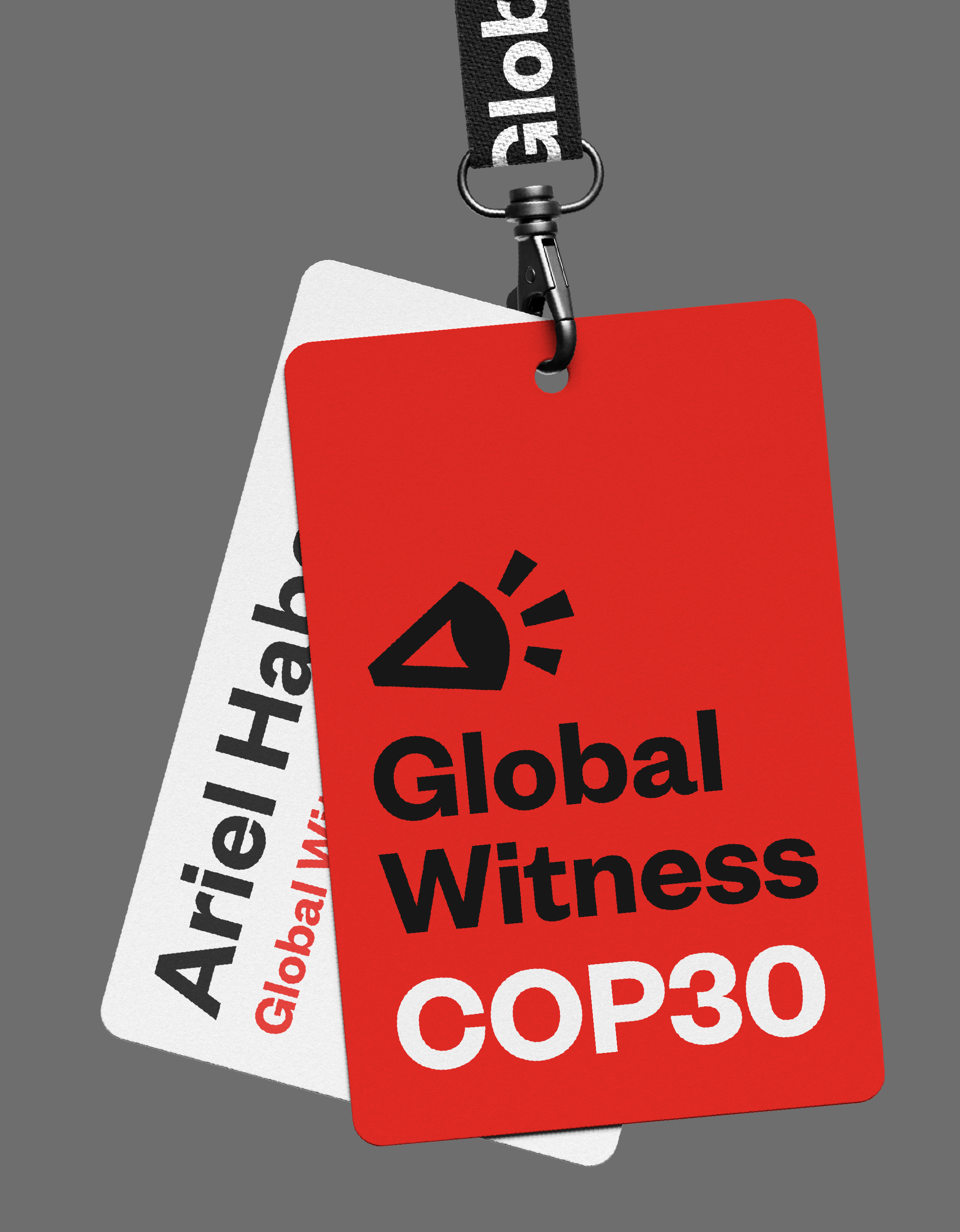 A lanyard for COP30 is shown against a grey background. There are two cards connected by a clip, the one is red and has the Global Witness logo, with COP30 underneath; the other has the personal ID card with a persons name on it, and their position