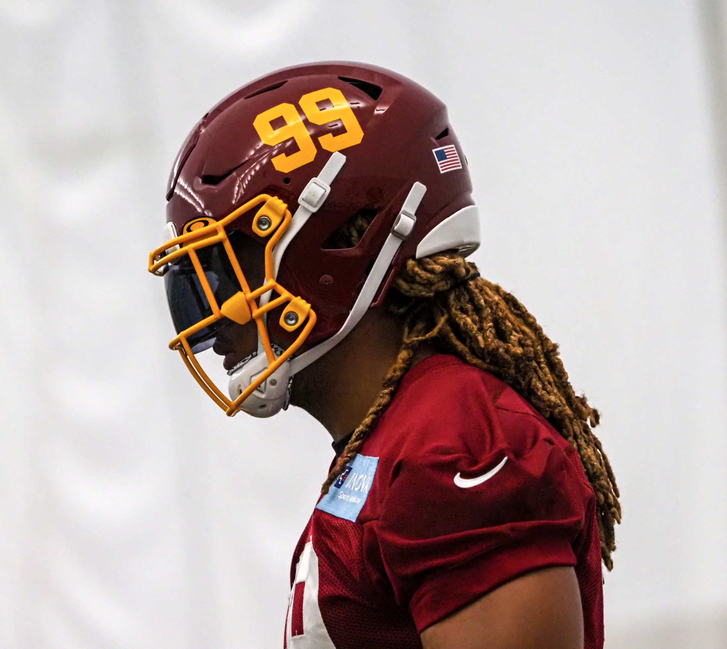 Football player wearing a red helmet with number 99 and an American flag sticker.