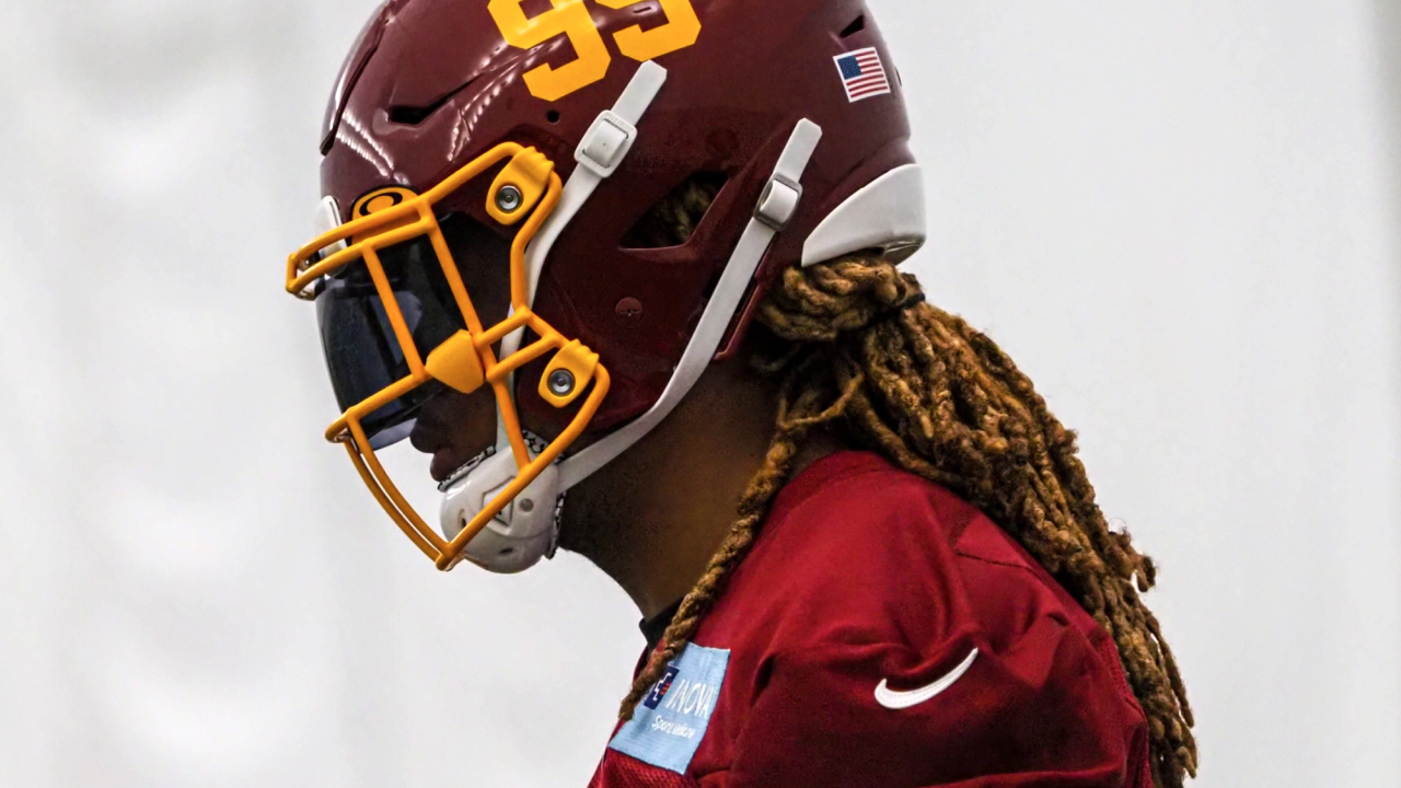 Football player wearing a red helmet with number 99 and an American flag sticker.