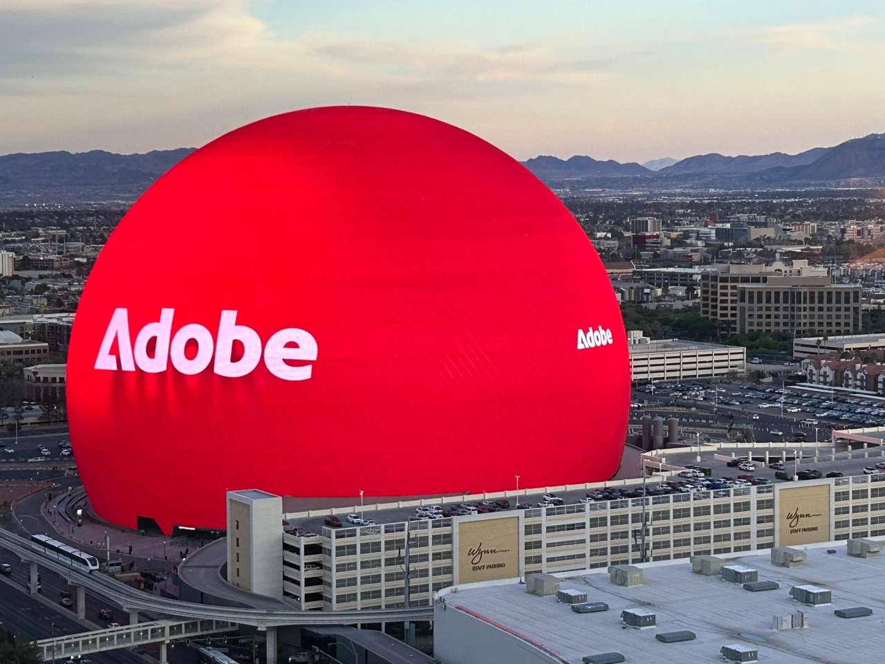 Out-of-home display featuring Adobe logo on a large red dome in an urban setting.
