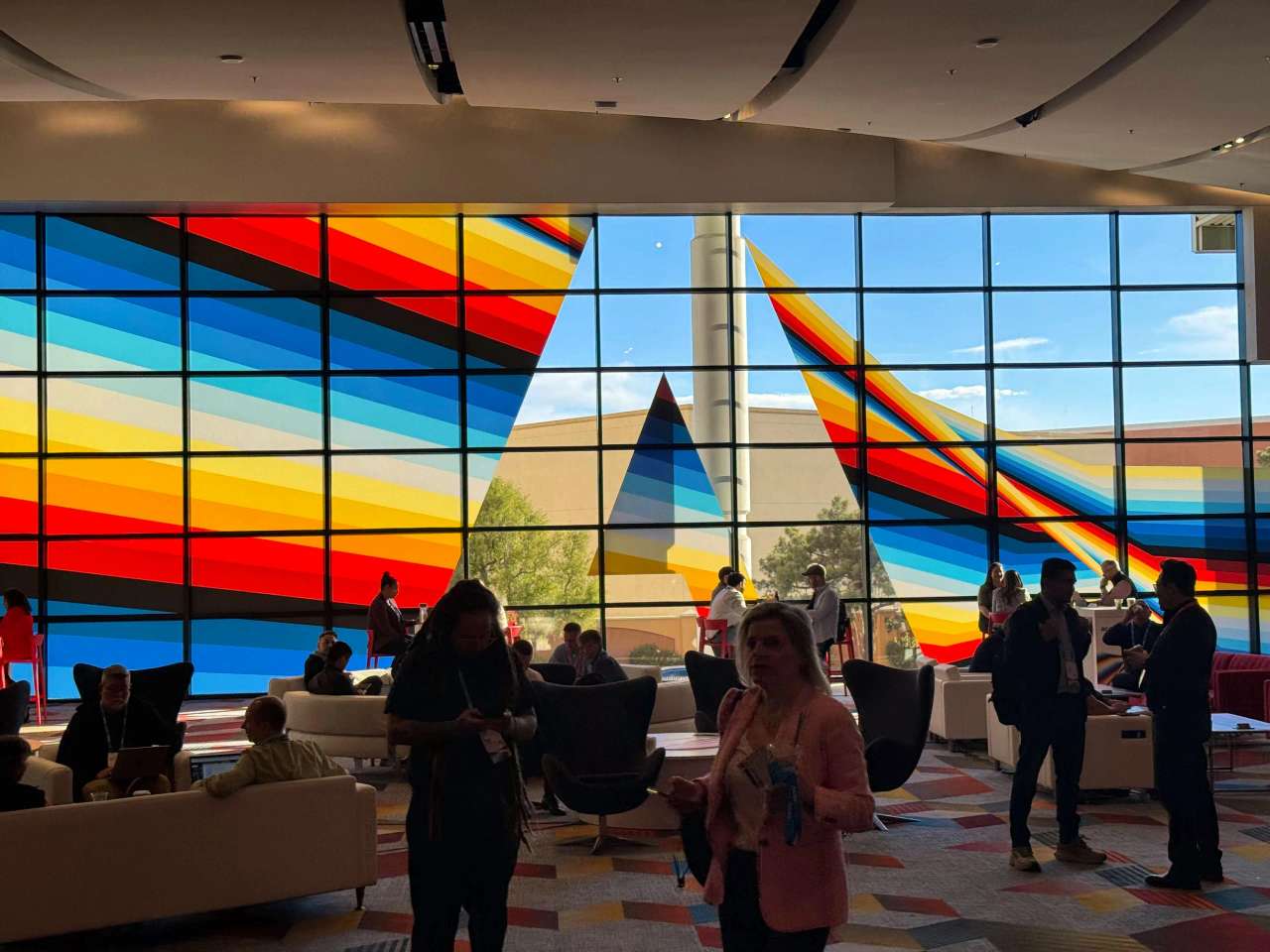Lobby area at Adobe Summit with colorful geometric window design and attendees networking.