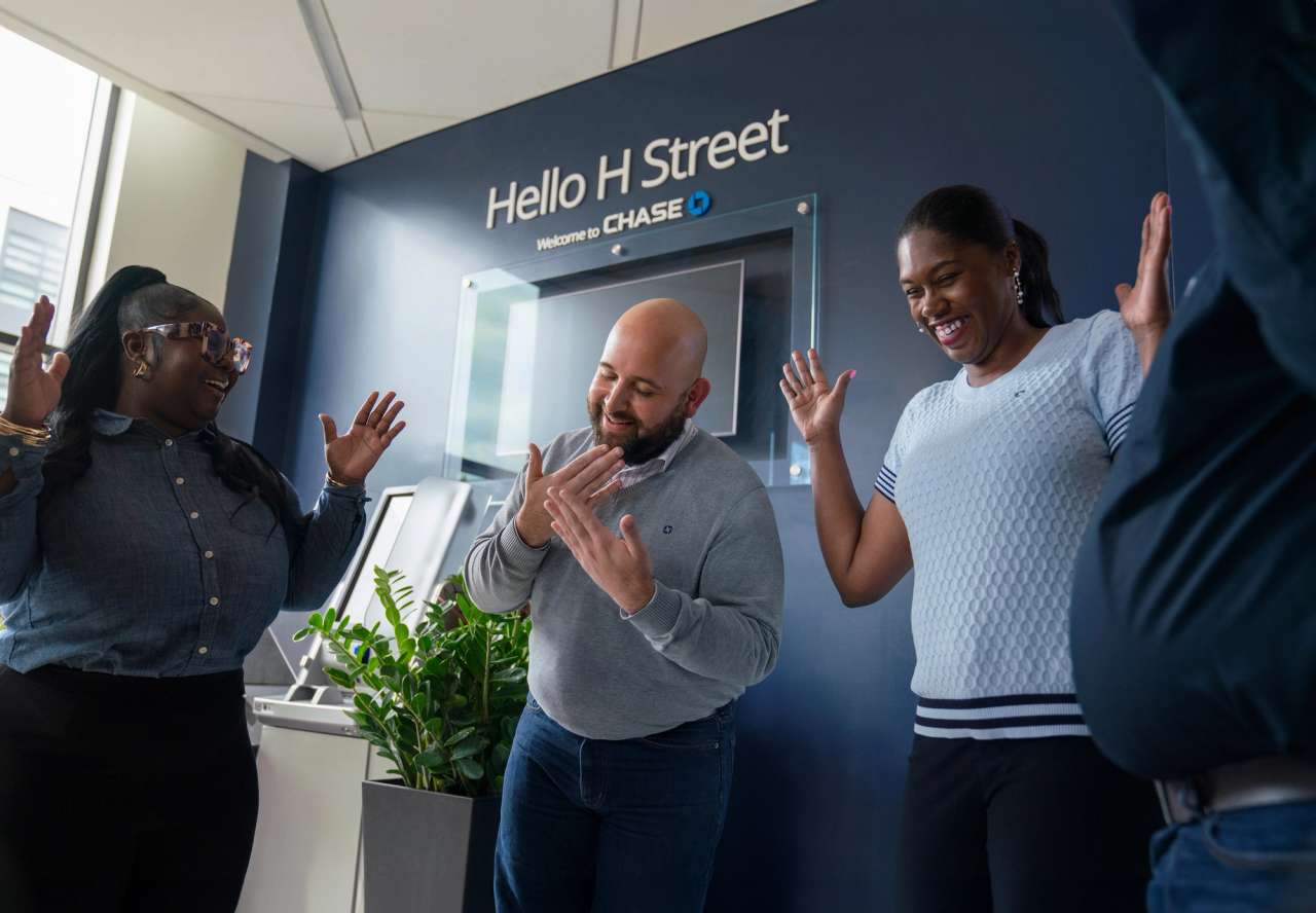 Three employees excitedly interacting at a JPMorganChase location.
