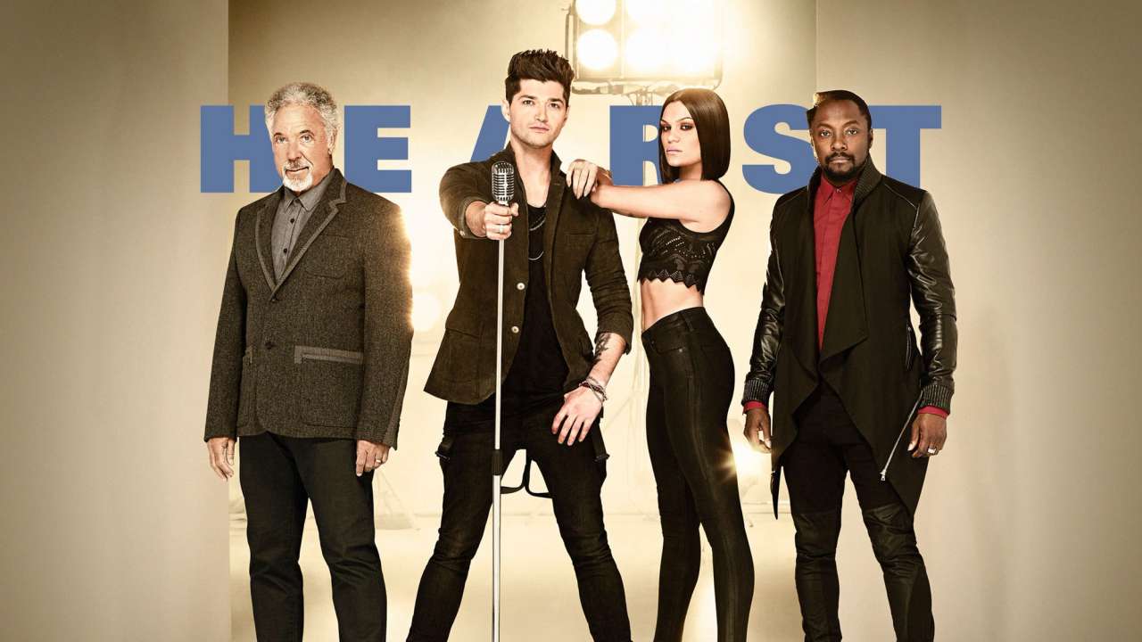 Promotional photo featuring four individuals posing with a microphone, stylishly dressed, with a spotlight and large letters in the background.