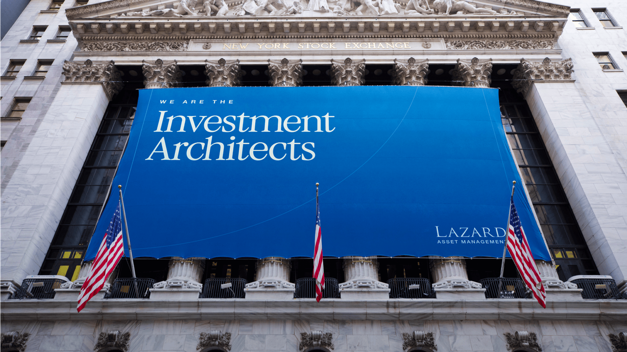Out-of-home banner on the New York Stock Exchange for Lazard Asset Management, displaying 'We are the Investment Architects'.