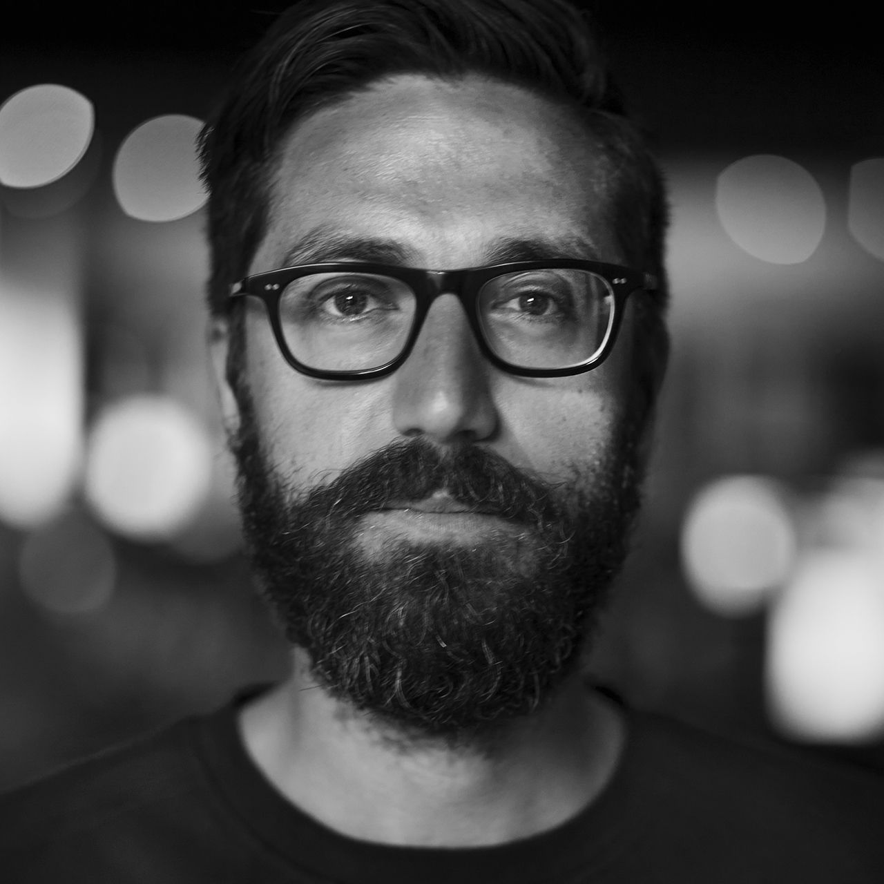 Black and white portrait of a person with glasses and a beard.