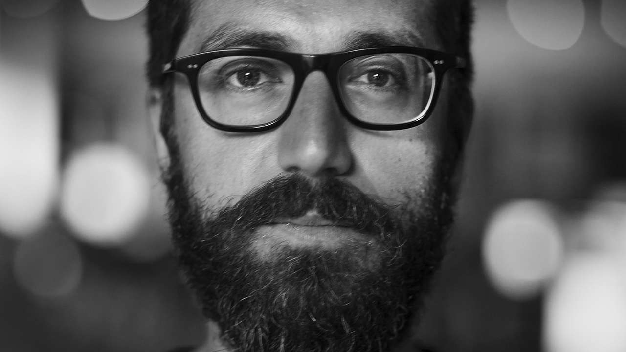 Black and white portrait of a person with glasses and a beard.