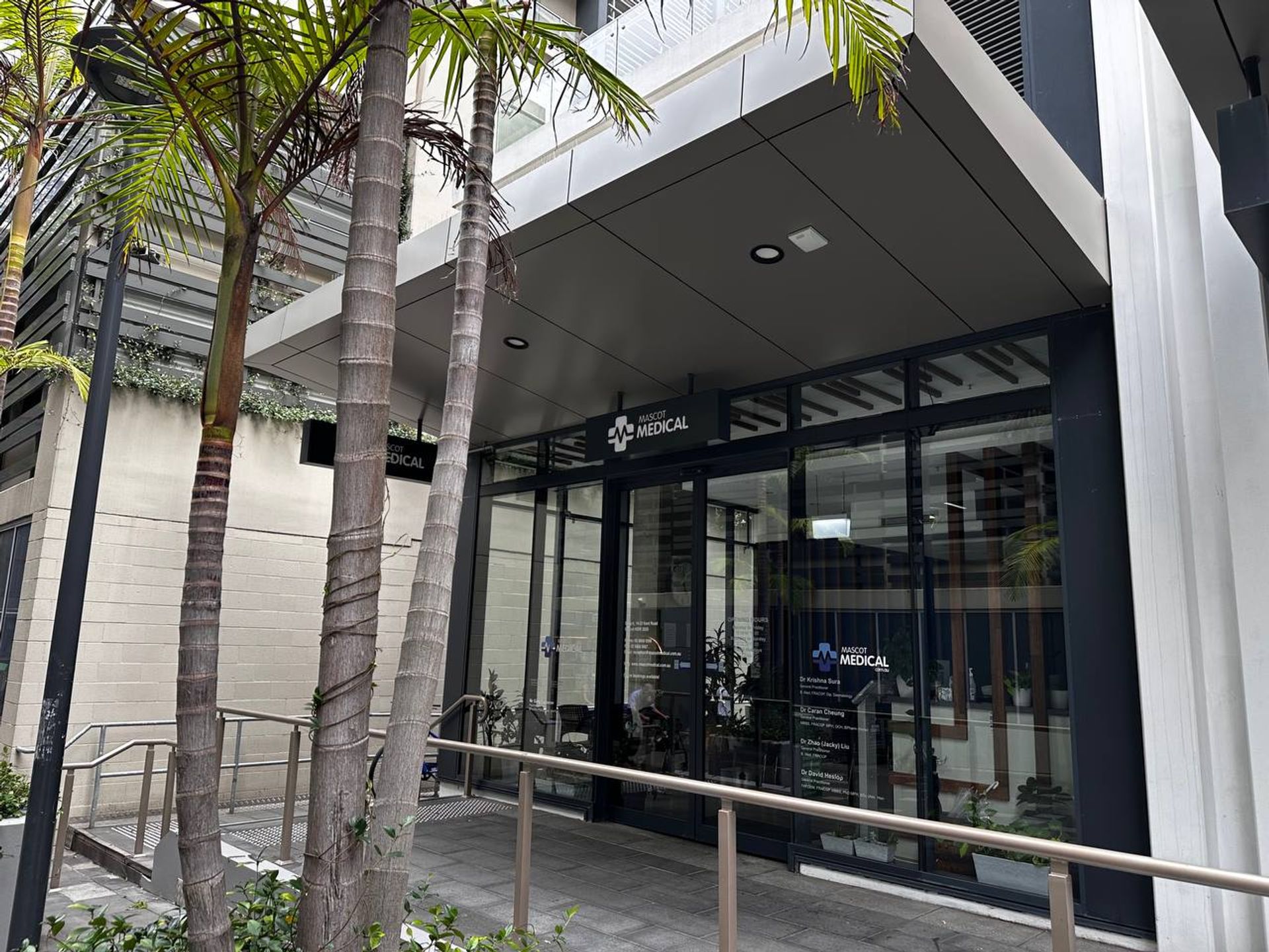 a large building with a sliding glass door and palm trees in front of it .