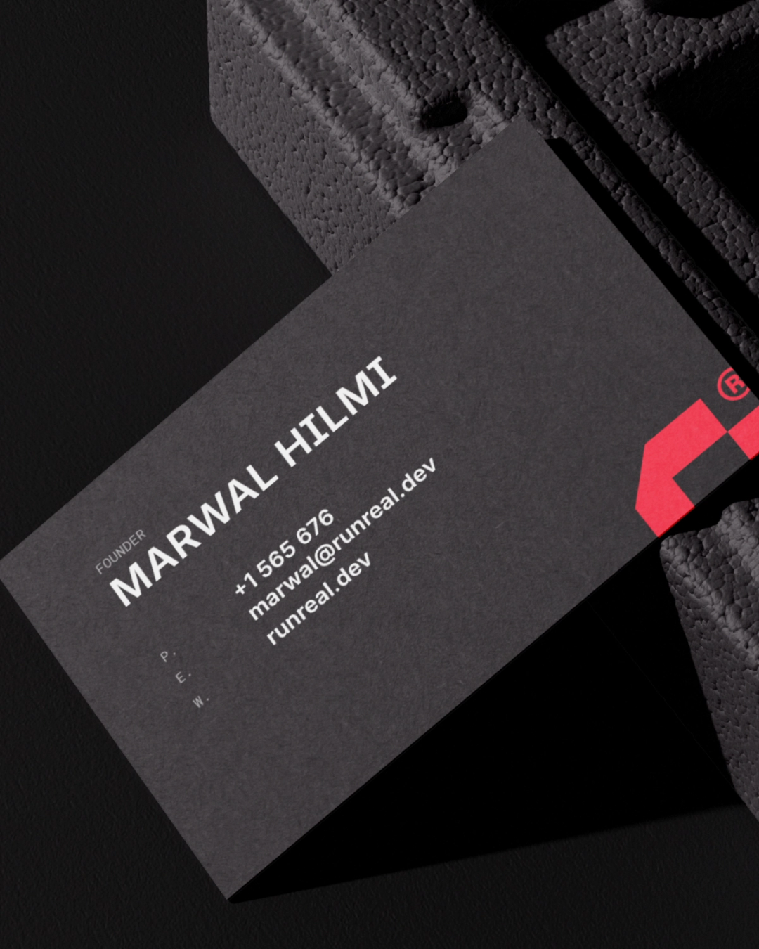 Close-up of a dark Runreal business card for founder Marwal Hilmi with bold white typography and a red geometric logo, designed by Kundo Studio to showcase the tech-forward brand identity and print collateral system.