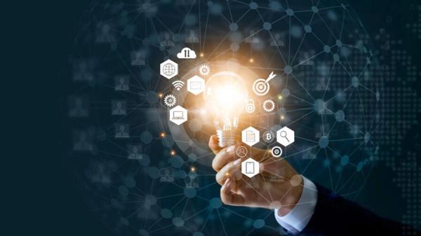 Hand holding a lightbulb with icons of cogs, computers, and magnifying glasses around it