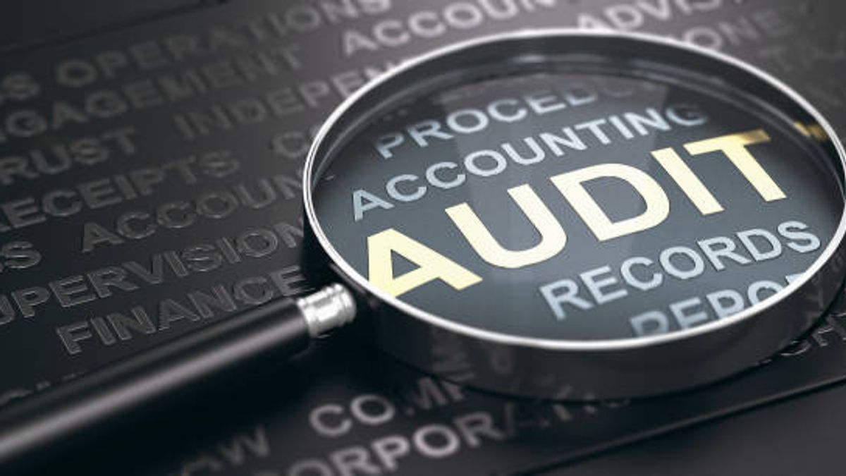 A magnifying glass enlarging the word 'AUDIT'