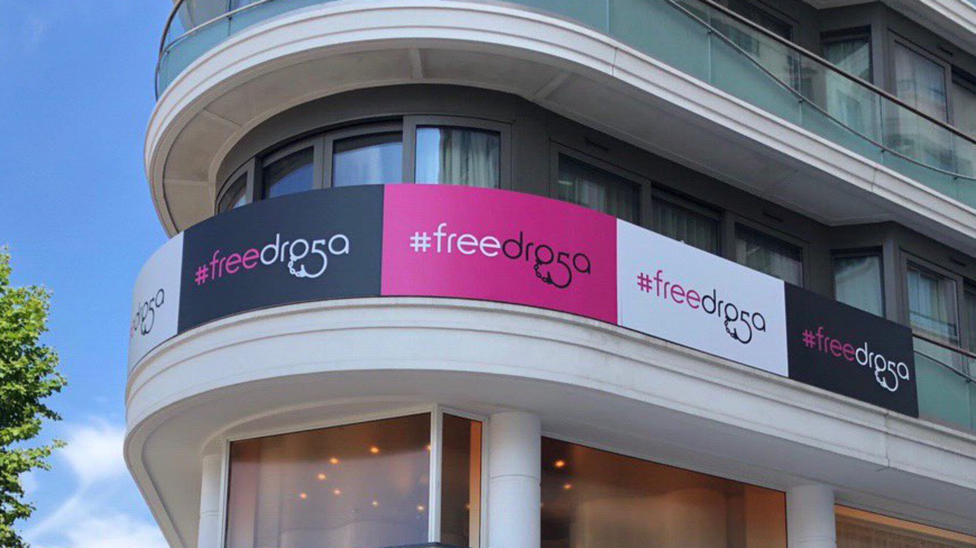 Building exterior featuring repeated #freedroga campaign signage in pink, black, and white.