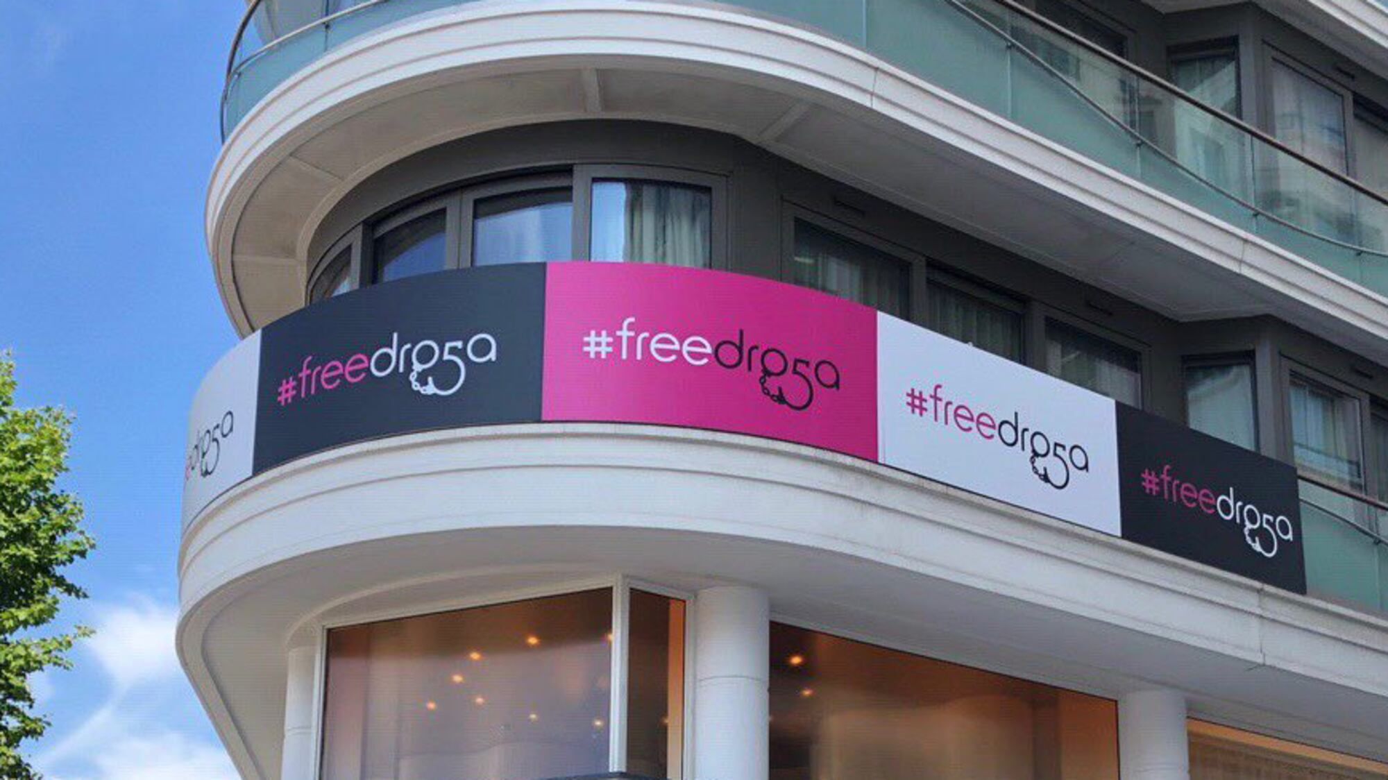 Building exterior featuring repeated #freedroga campaign signage in pink, black, and white.