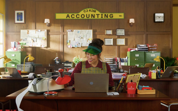 Woman working at a desk in a fictional accounting office for a Hiscox advertising campaign.