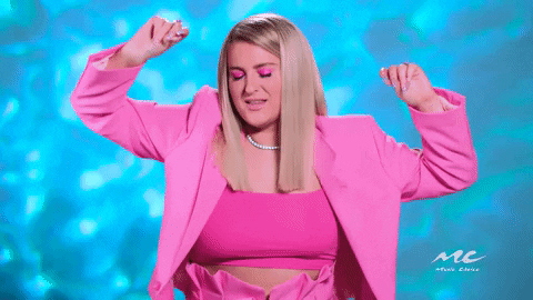 Gif of Meghan Trainor dancing in a bright pink outfit against a blue background.