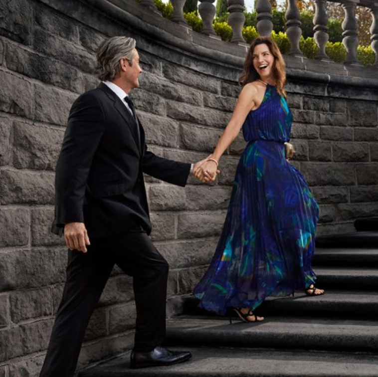 Formally dressed couple holding hands while walking up outdoor stone steps.