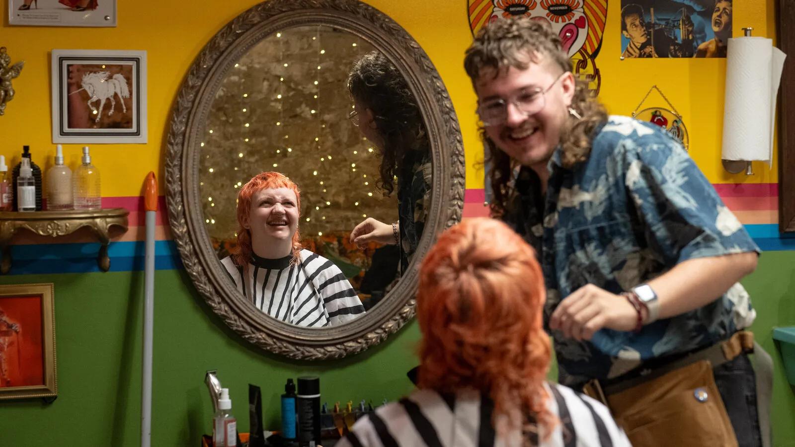 Hairstylist working with a client with red hair in a colorful salon for a hair care campaign.