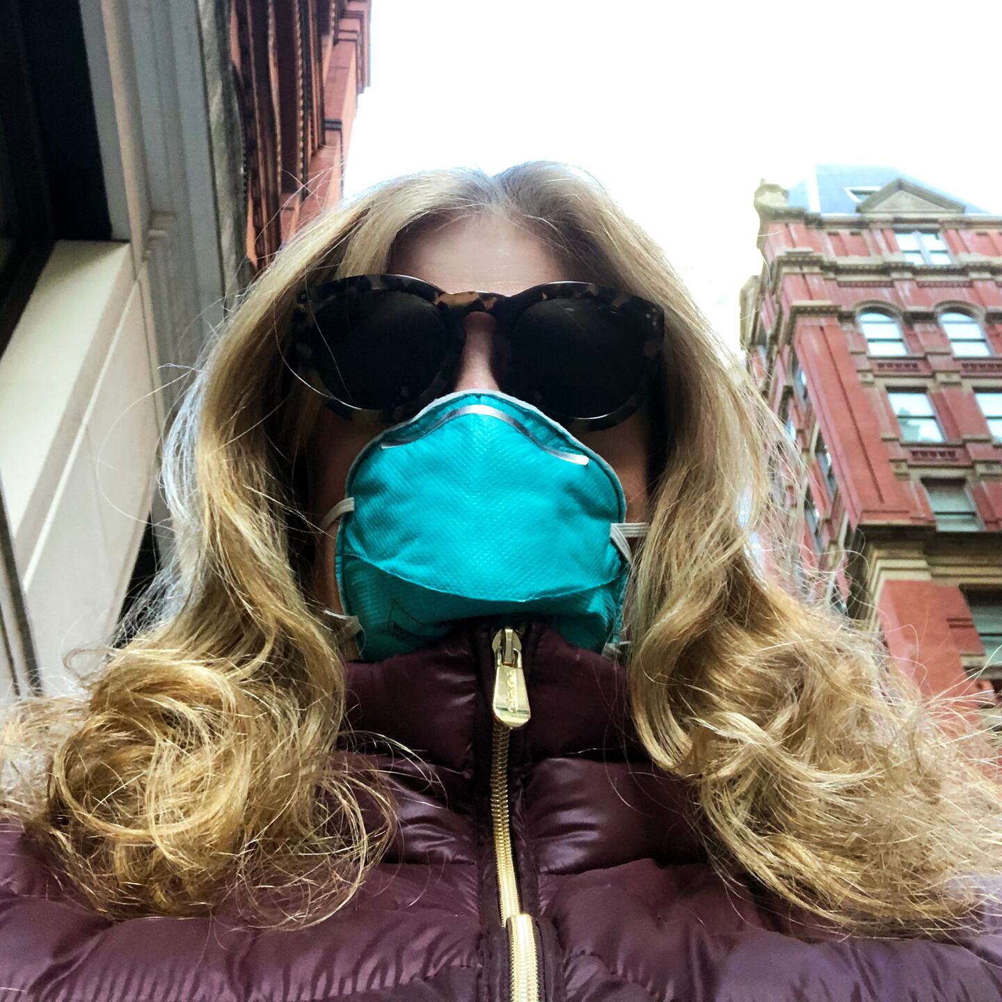 Woman wearing sunglasses and a protective face mask on a city street during the pandemic.