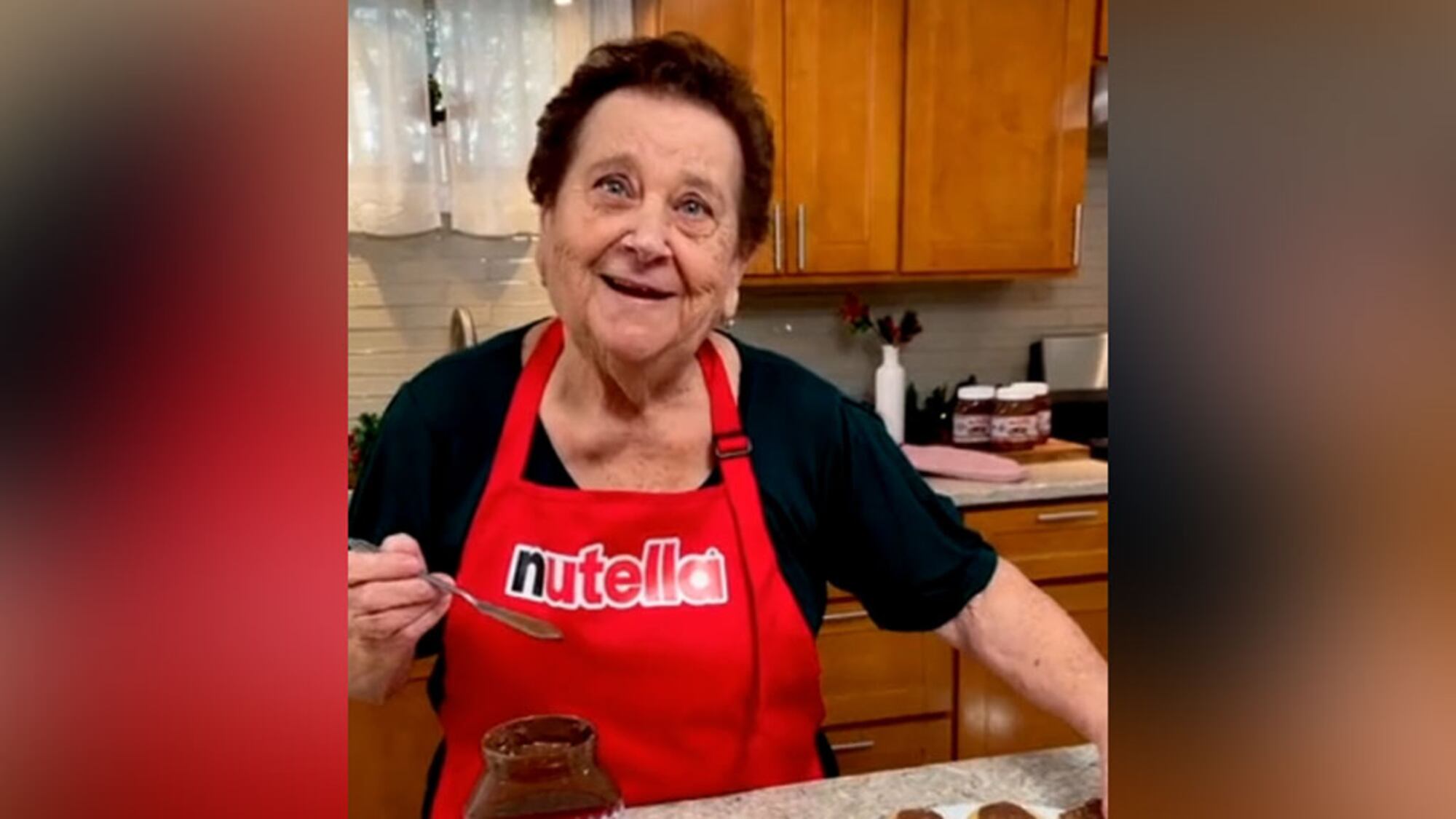 Nonna Pia wearing a Nutella apron holding a spoon in a kitchen during a Nutella promotional campaign.