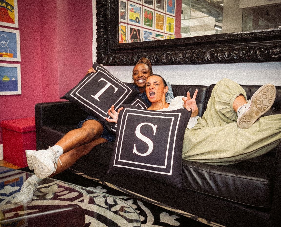 Two creative agency team members relaxing in a colorful office lounge.