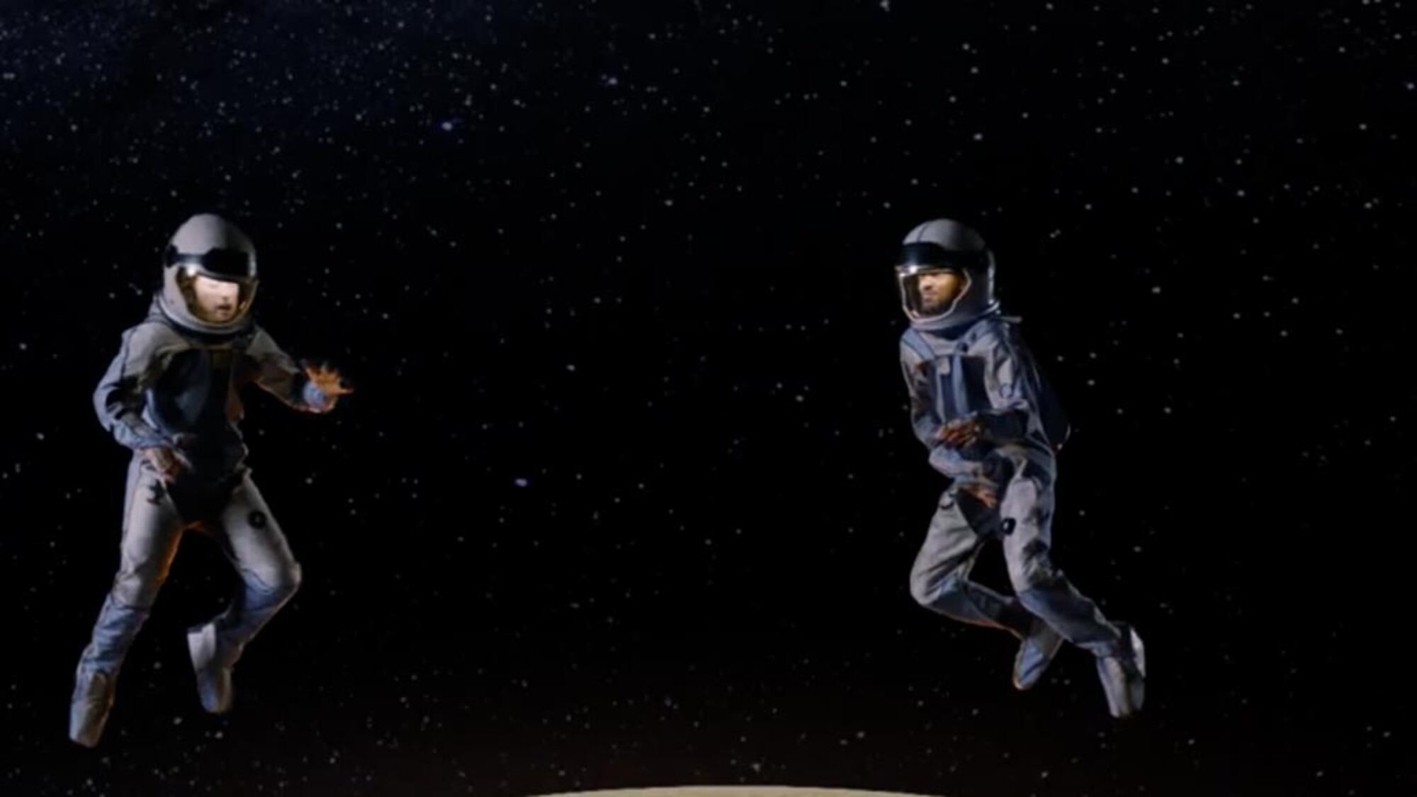 Two astronauts floating against a star-filled background in a television commercial.